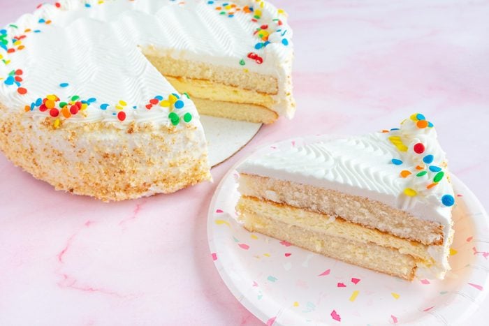 costco cake with a slice cut from it on pink background