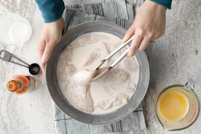 Chicken Being Tossed To Coat In The Buttermilk And Hot Sauce