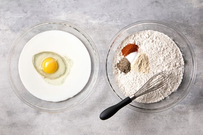 egg and buttermilk in left glass bowl and flour, garlic powder, pepper, salt and paprika in another bowl